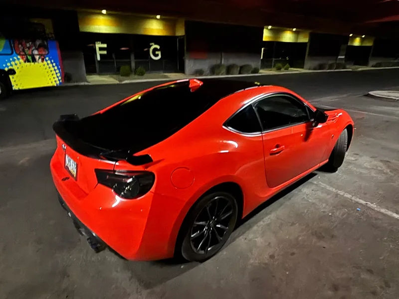 Red sports coupe with dark windows photographed at night